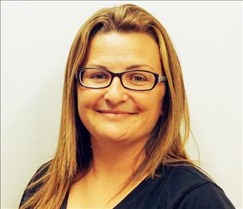 Woman with long hair and glasses wearing a black shirt against a white background