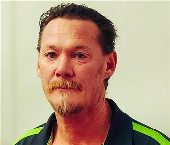 Man wearing a black and green shirt facing the camera against a white background