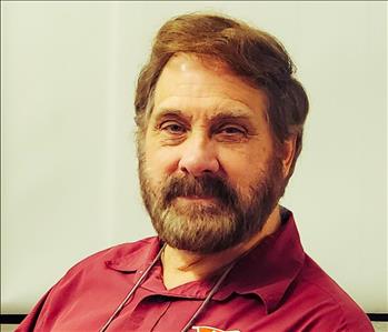 Man with a beard and a red shirt facing the camera against a white background